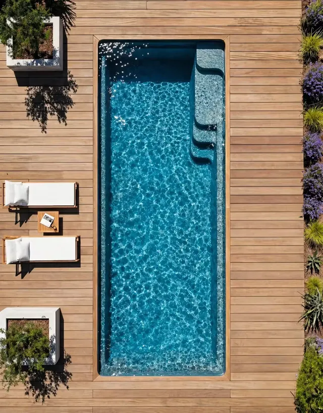 Vue aérienne d'un couloir de nage entouré d'un deck en bois clair, transats en teck et bacs plantés en aluminium noir